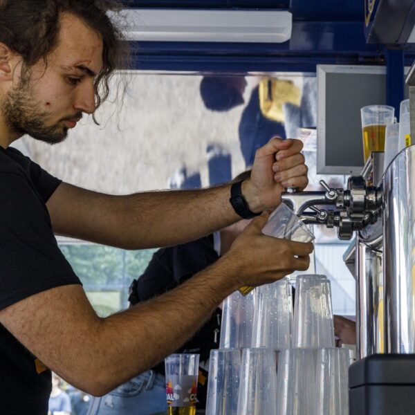 Mann zapft Bier an einem Getränkestand.