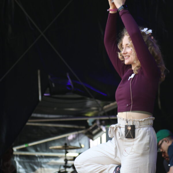 Eine Frau steht auf der Bühne und zeigt eine Yoga Pose